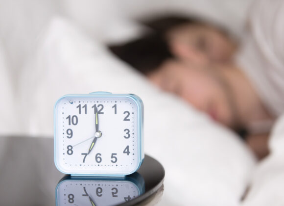 Young couple sleeping in bed next to an alarm clock