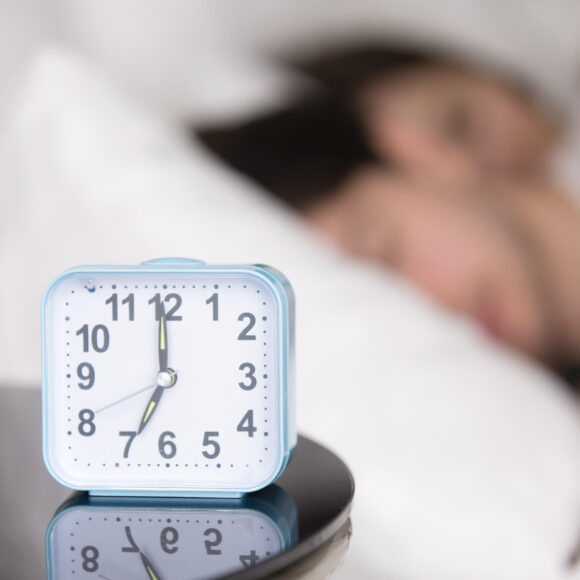 Young couple sleeping in bed next to an alarm clock